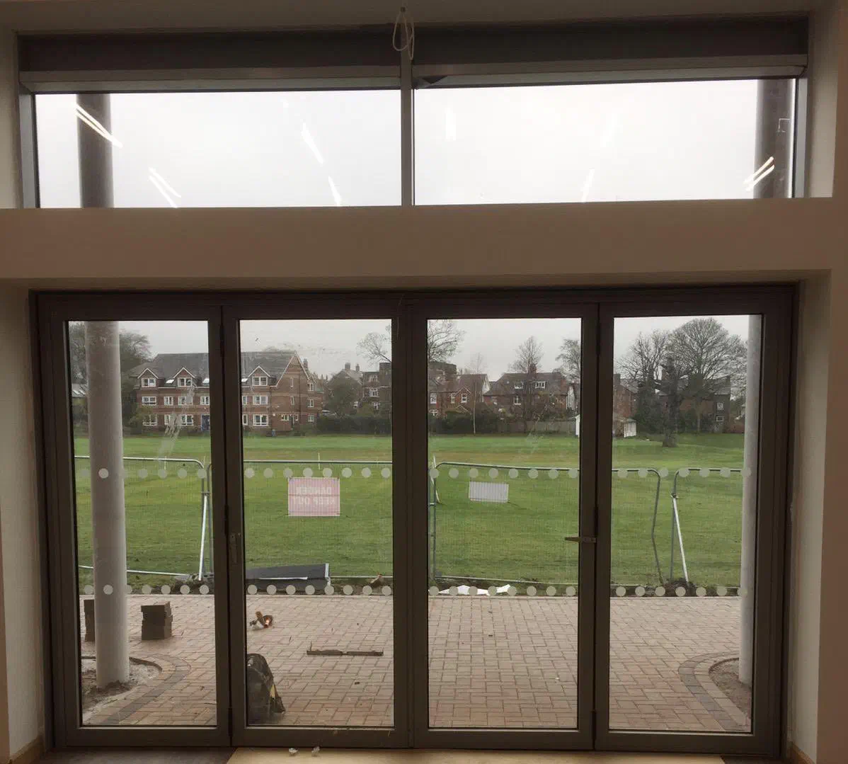 A four-panel bifold door and a high transom window looking out over a playing field